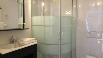 Une salle de bain avec une douche à parois de verre, un lavabo avec un miroir et des toilettes.