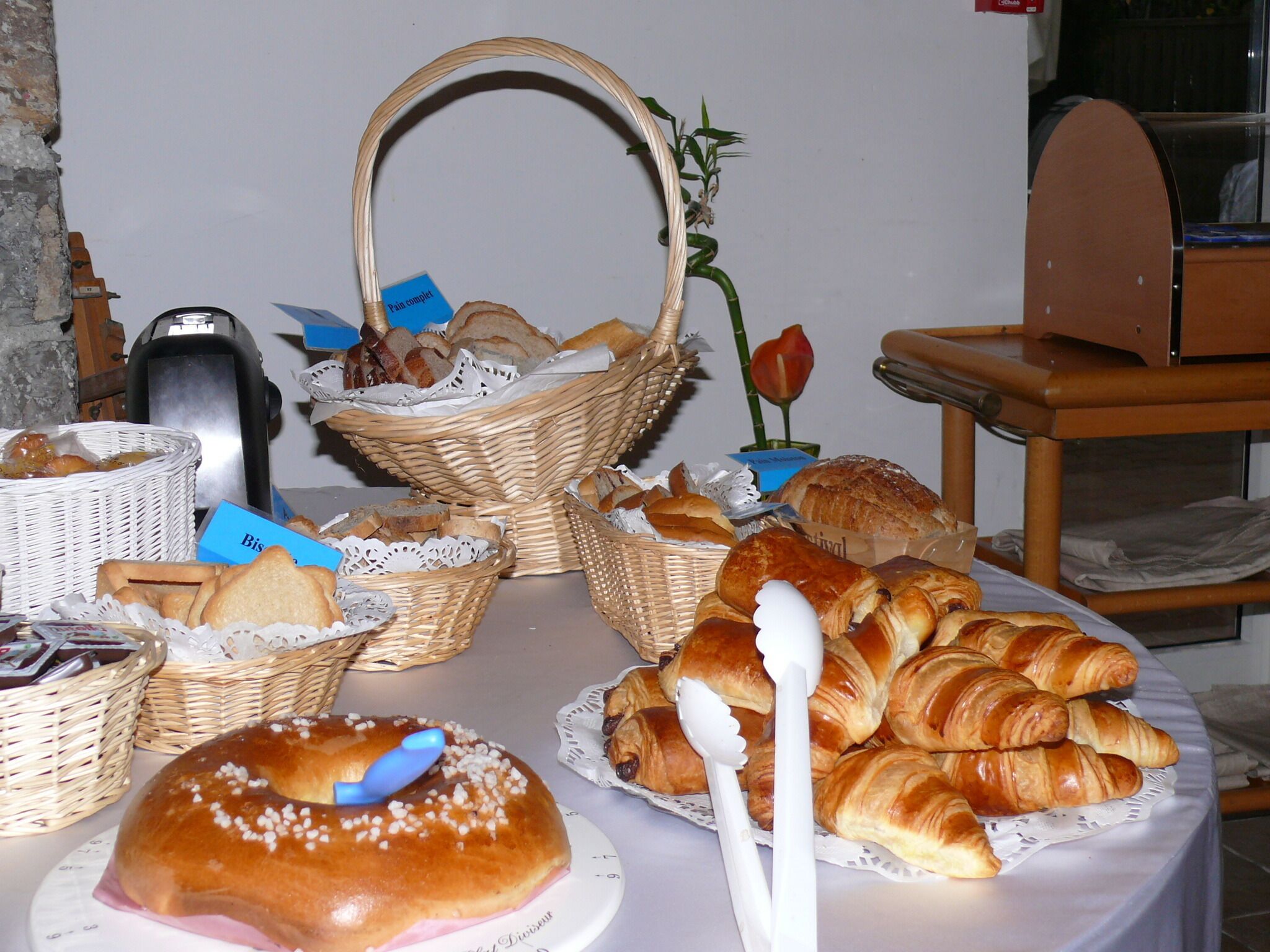 Taula amb diversos aliments, com ara pa i pastissos, sobre un mantell.