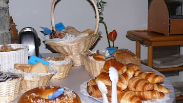 A table with various food items, including bread and pastries, arranged on a tablecloth.
