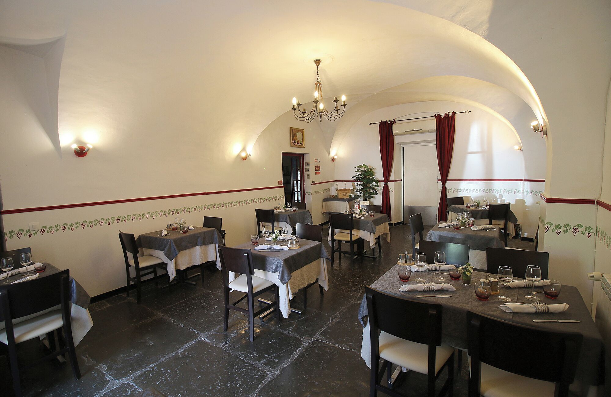 Un restaurant avec des tables dressées, un lustre et une plante.