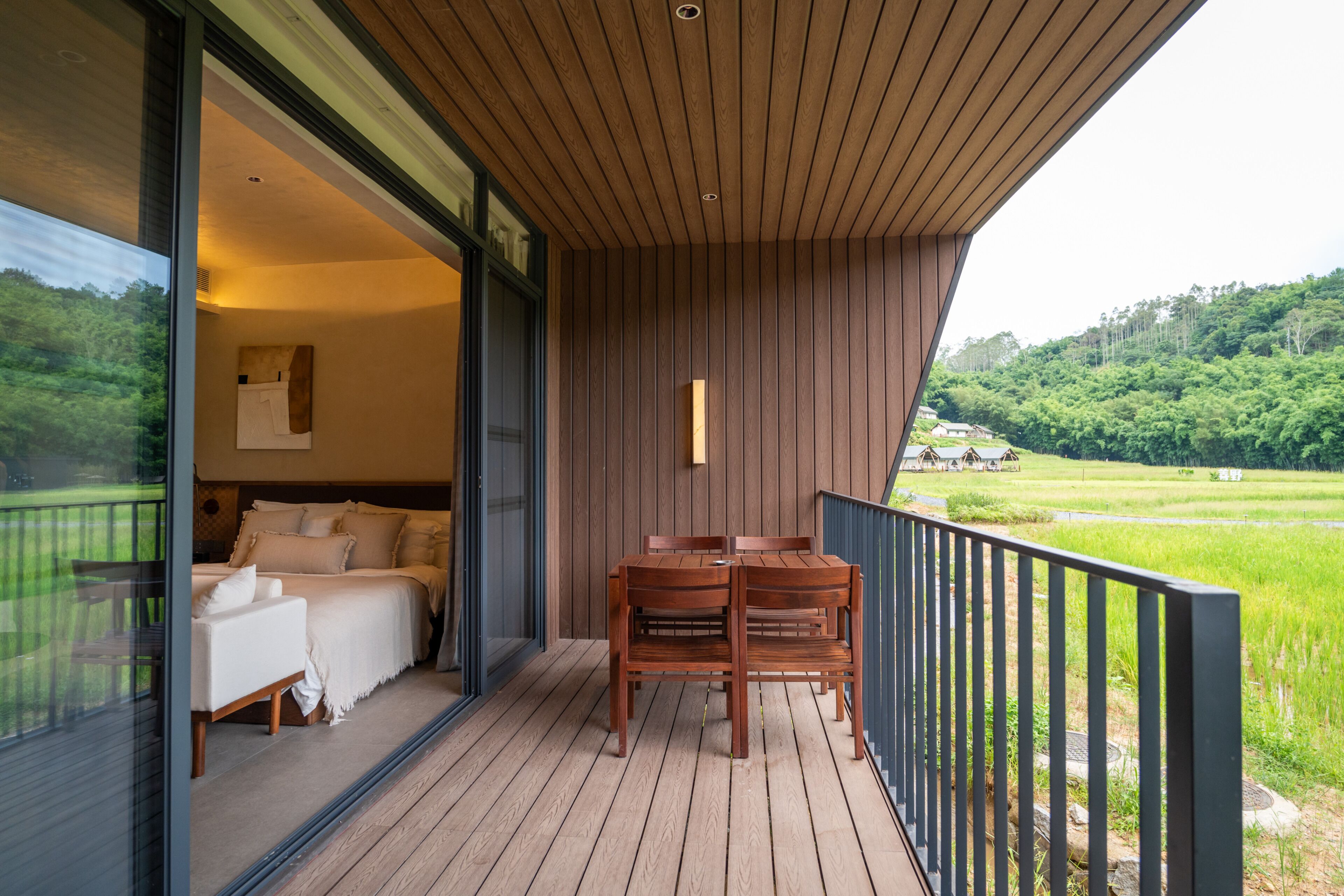 Un balcon avec un plancher en bois, un lit avec une literie blanche et une table avec des chaises.