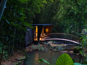 A secluded cabin with a wooden exterior, a small porch, and a bridge over a stream. - SINYE IN THE VALLEY (Guangzhou)