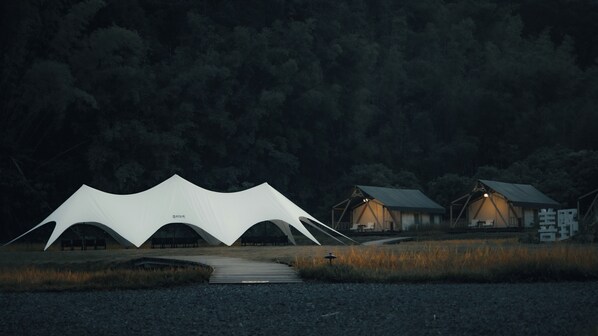 A series of tents with a walkway leading to them, set in a forested area. - SINYE IN THE VALLEY (Guangzhou)