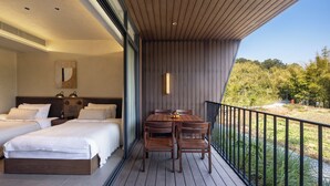 A balcony with a wooden table and chairs, a bed with white bedding, and a view of the outdoors. - SINYE IN THE VALLEY (Guangzhou)