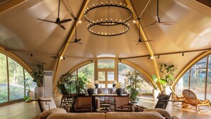 A tent-style room with a central table, chairs, ceiling fans, and potted plants. - SINYE IN THE VALLEY (Guangzhou)