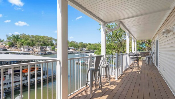 A covered deck with a view of a marina and docked boats. - Lake Mode Lakefront Balcony (Osage Beach)