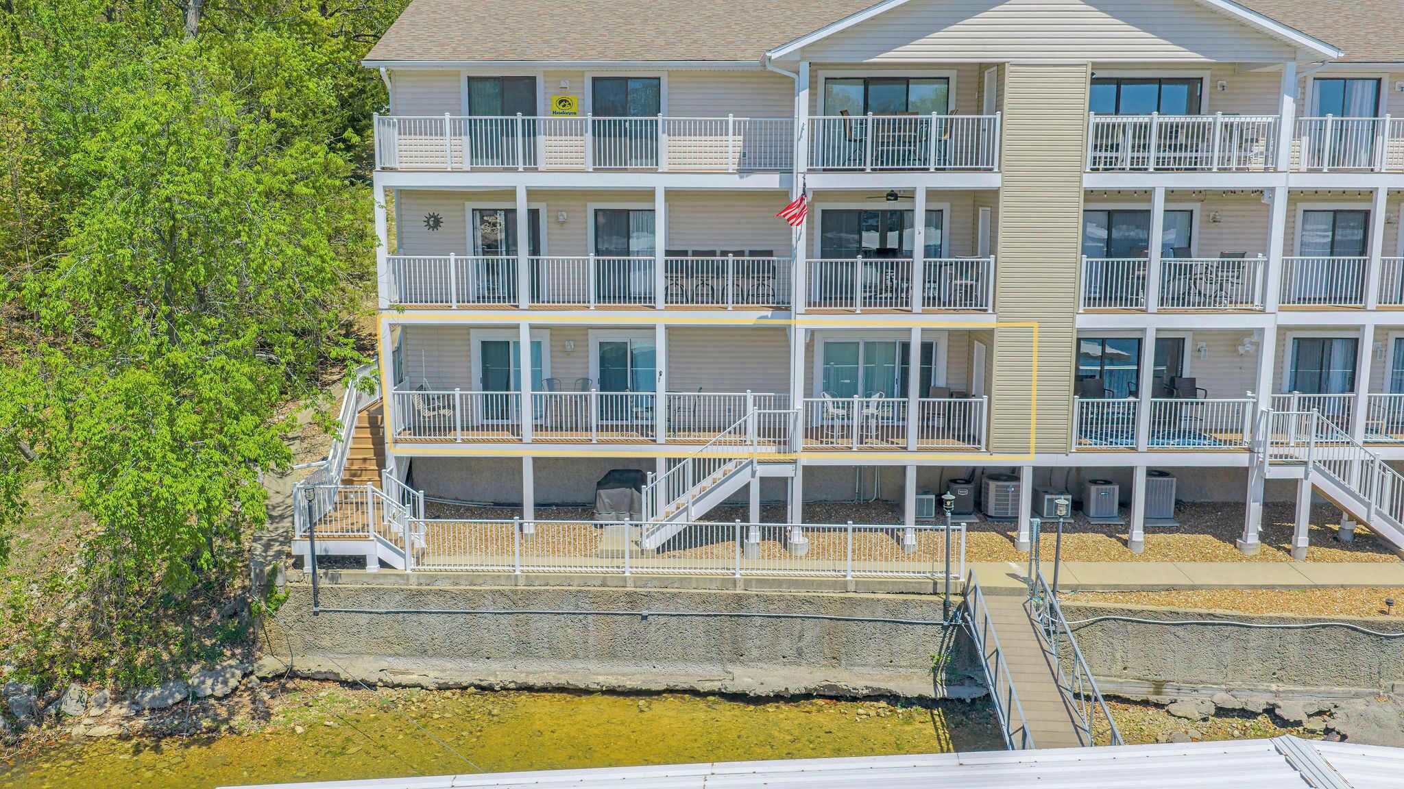 A multi-story hotel with balconies, a flag, and a view of the water.