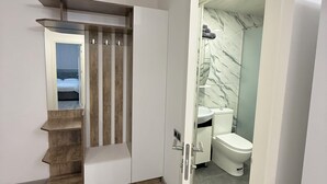 Ein modernes Badezimmer mit Toilette, Dusche und einer Marmorwand.