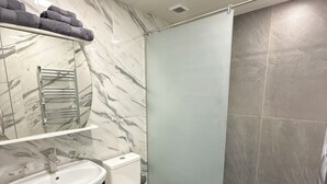 Ein Badezimmer mit Marmorwaschtisch, Toilette und Duschbereich.