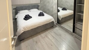 Ein modernes Schlafzimmer mit einem Bett, Nachttischen, einem Spiegel und einem Kleiderschrank.