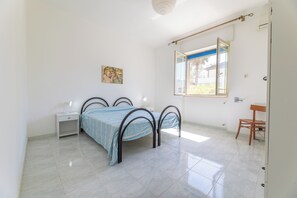A bedroom with a bed, a desk, a chair, a window, and a painting on the wall. - Villa up to 10 places near Gallipoli MV14 (Marina di Mancaversa)