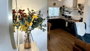 Una cocina moderna con ventana, un reloj y un florero con flores sobre una mesa.