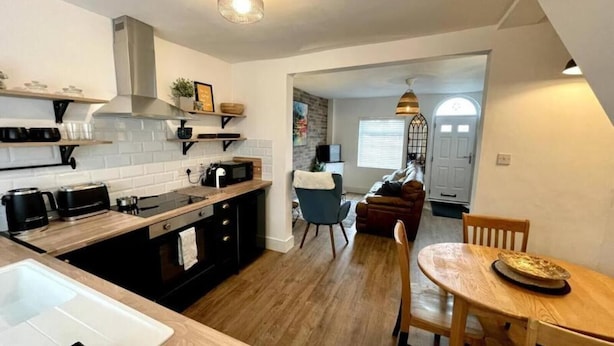 Una cocina moderna con encimera de madera, horno empotrado y comedor con mesa y sillas de madera.
