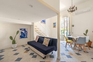 A living room with a sofa, a dining table with chairs, a staircase, and a chandelier. - Mondello sea life garden (PALERMO)