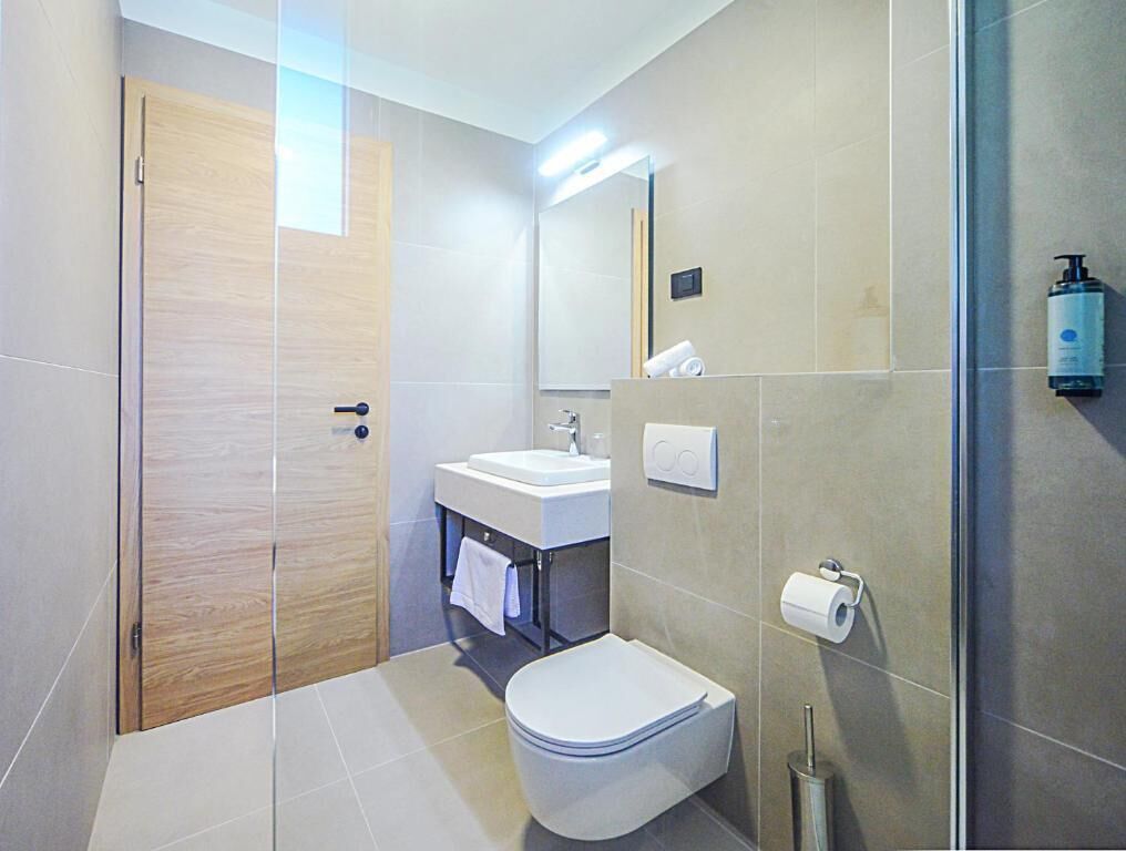 Et moderne badeværelse med toilet, vask og bruseområde.