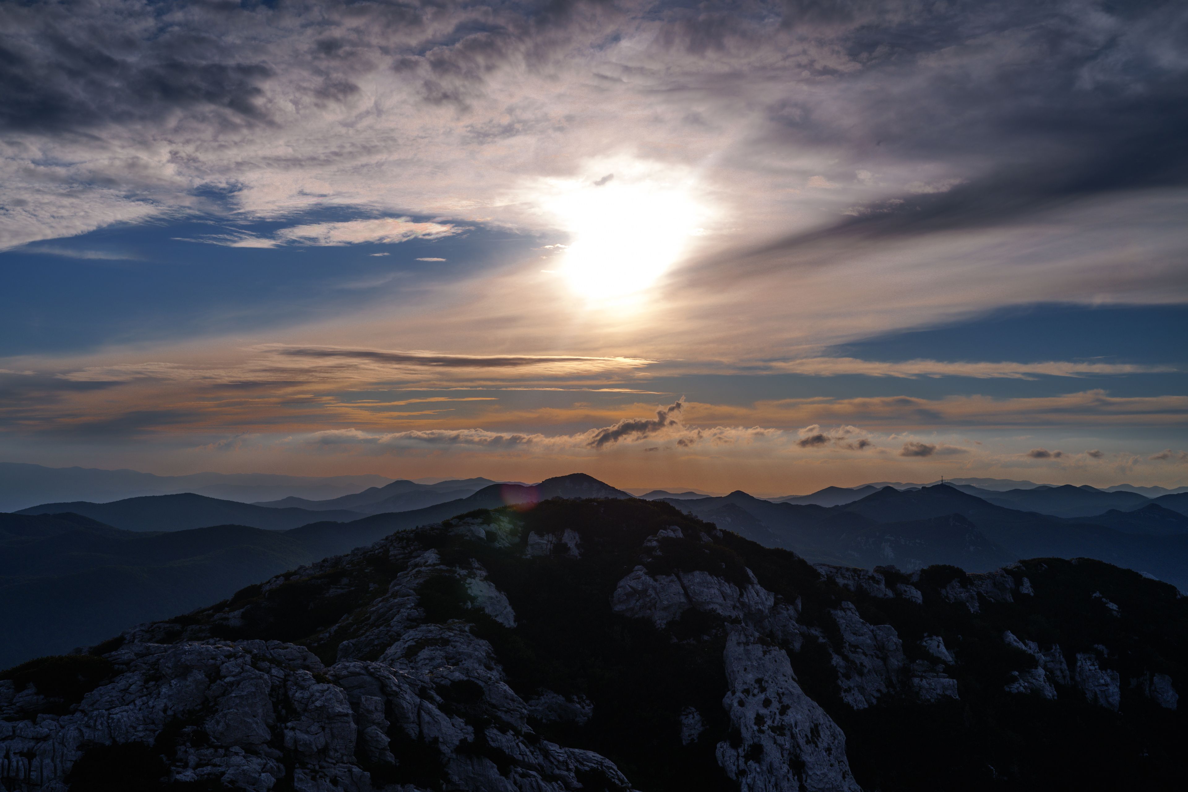 Paisaje montañoso con cielo despejado y el sol poniéndose o saliendo.