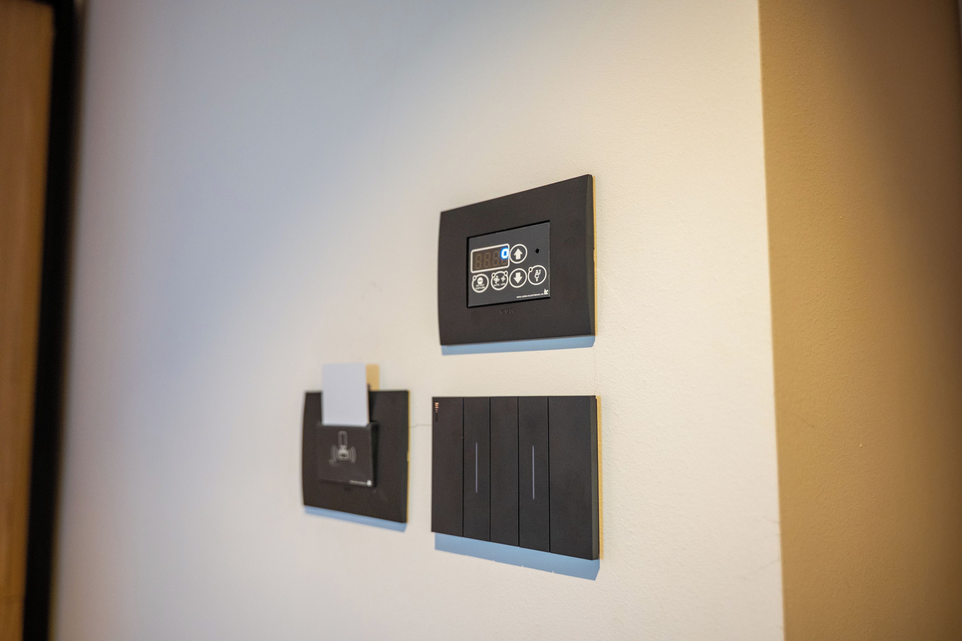 Una pared con tres paneles de control, uno con una pantalla digital y dos con botones.