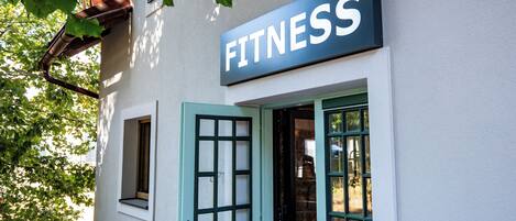 A building with a sign reading 'FITNESS' above the entrance, a door, and windows.