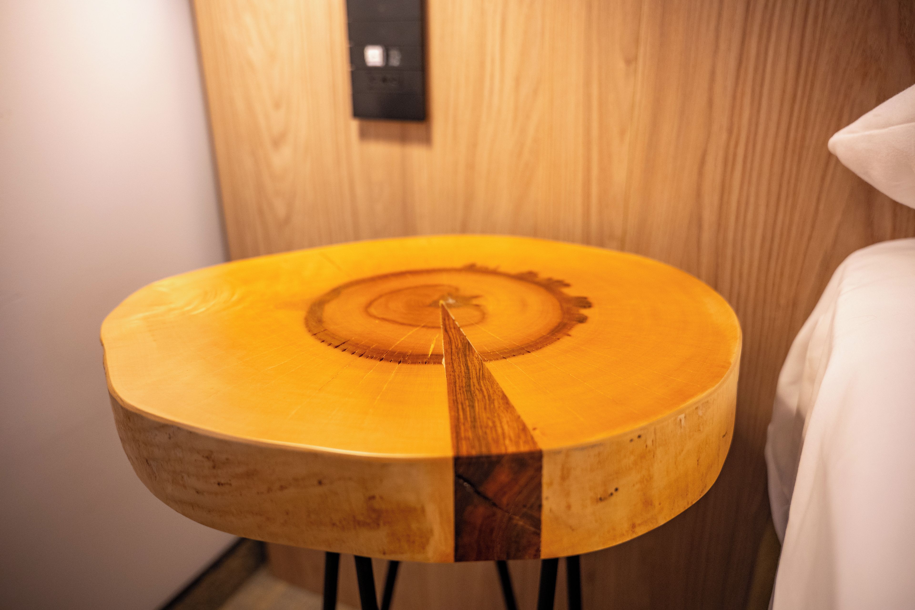 A wooden table with a circular design on its surface, positioned against a wooden wall with a light switch visible.