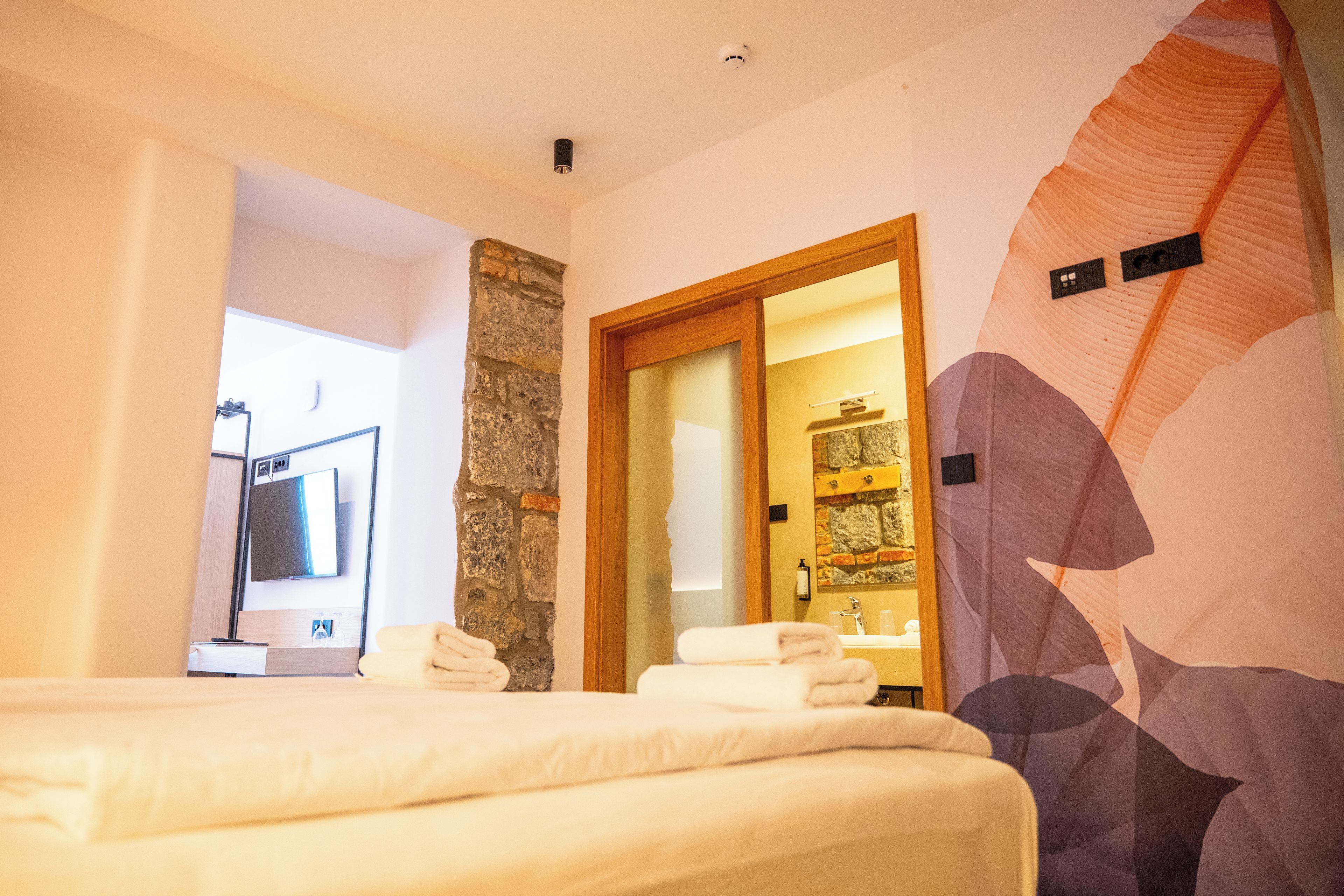 Une chambre d’hôtel avec un lit, une salle de bain avec douche et une grande fresque murale.