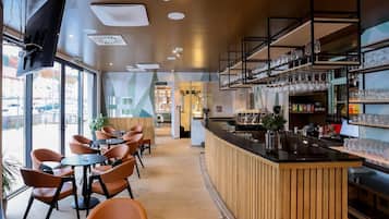 Un bar moderno con asientos y una barra, con acabados de madera y cristalería en estantes.