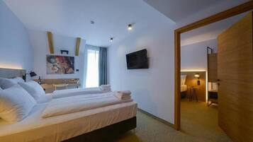 A hotel room with a bed, a desk, a TV, and a painting on the wall.
