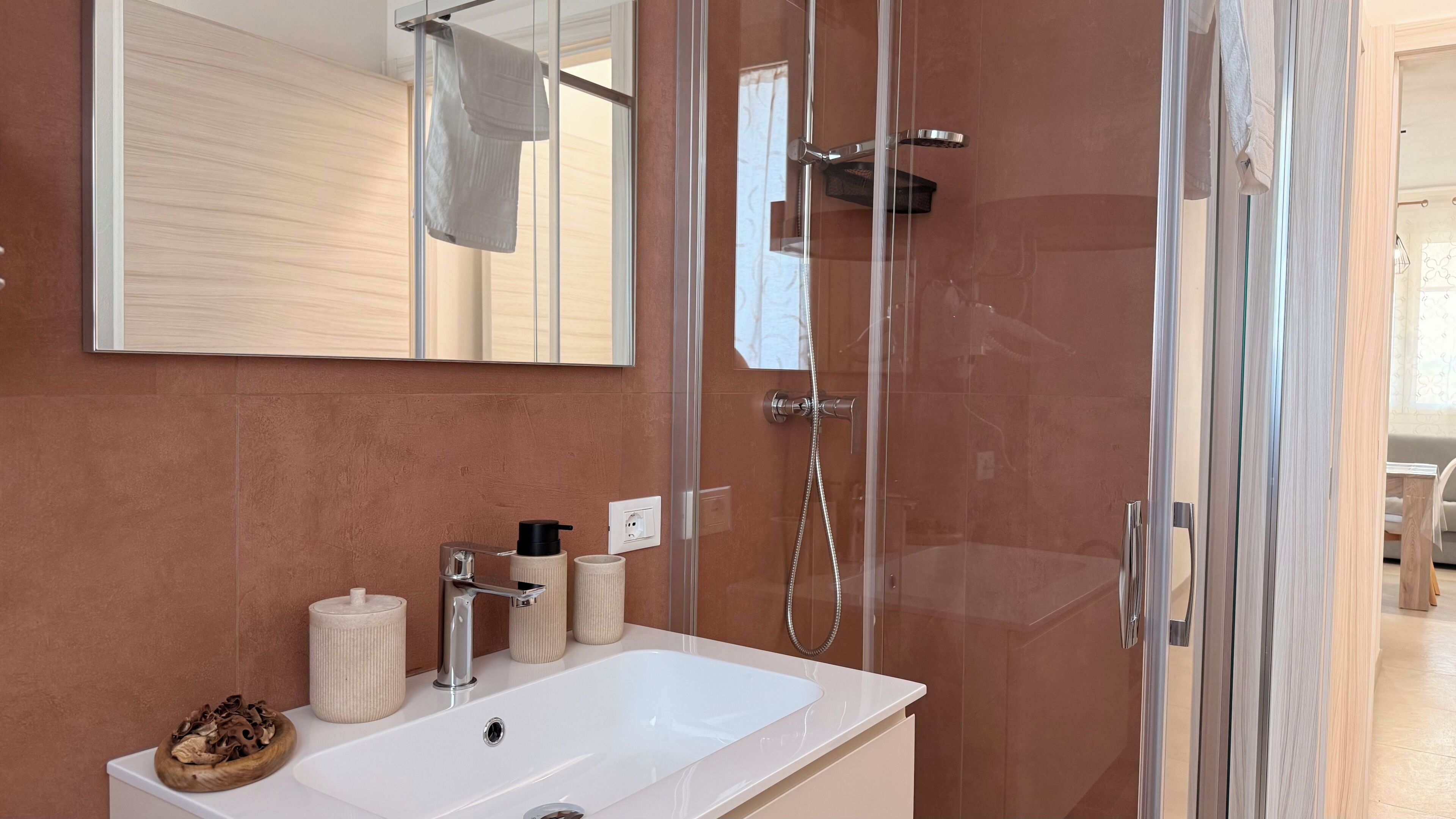A modern bathroom with a glass-enclosed shower, a white sink, and a mirror above it.