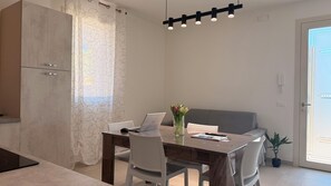 Une cuisine moderne dotée d’un four encastré, d’une table à manger avec des chaises, d’un ordinateur portable et d’un vase rempli de fleurs.