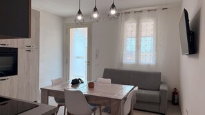 Een moderne keuken met een inbouwoven en een eethoek met een tafel en stoelen.