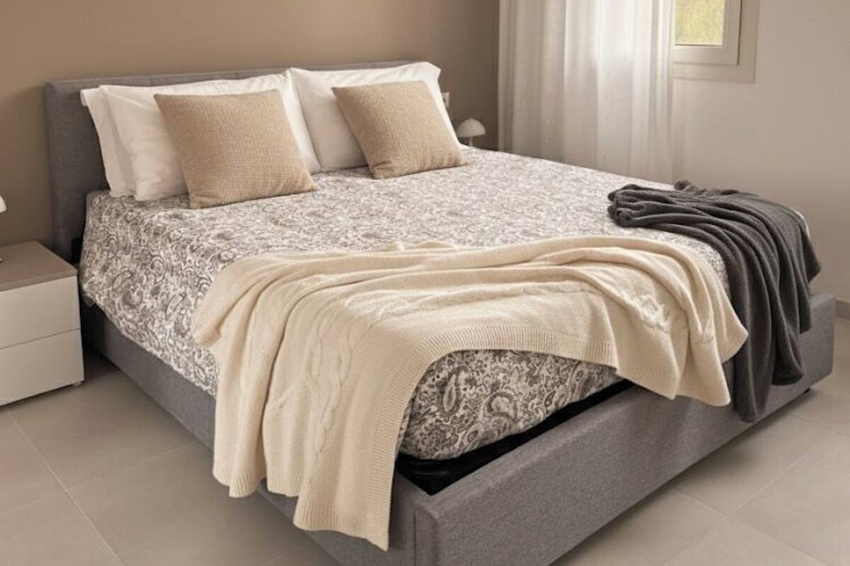 A bedroom with a bed, nightstand, and a window with curtains.