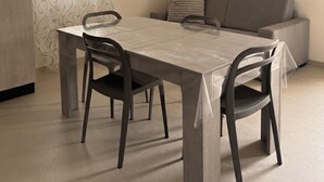 Een eetgedeelte met een tafel, stoelen, een bank en een hanglamp.