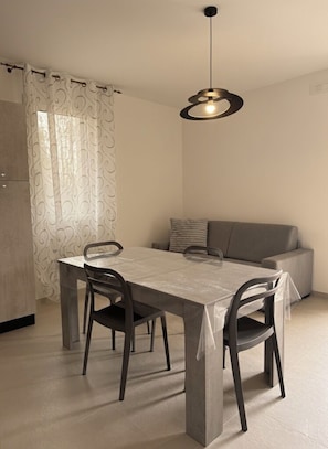 Un comedor con una mesa, sillas, un sofá y una lámpara colgante.