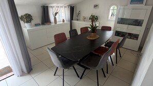 Ruokailutilassa on musta pöytä ja tuolit, kattovalaisin sekä keittiö, jossa on kaappeja ja ikkuna.