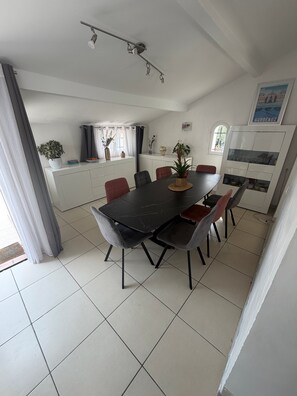 A dining area with a black table and chairs, a ceiling light fixture, and a kitchen area with cabinets and a window. - Villa in Grasse with swimming pool (Grasse)