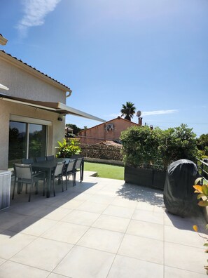 A patio with a table and chairs, a covered area, and a view of a house in the background. - Villa with a Pool and Private Hot Tub Near Ajaccio (Cuttoli-Corticchiato)