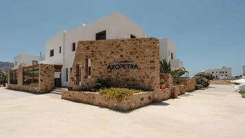 A boutique hotel with a stone facade, a clear sky, and a sign reading 'AXOPETRA Boutique Hotel'.