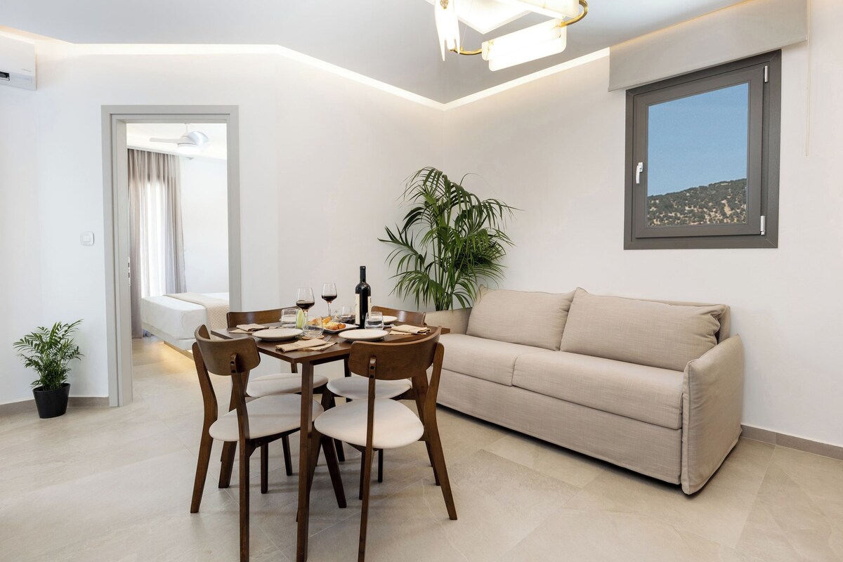 A modern living room with a dining area, a sofa, a potted plant, and a window with a view.