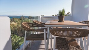 En balkon med fletstole, et bord og en potteplante.