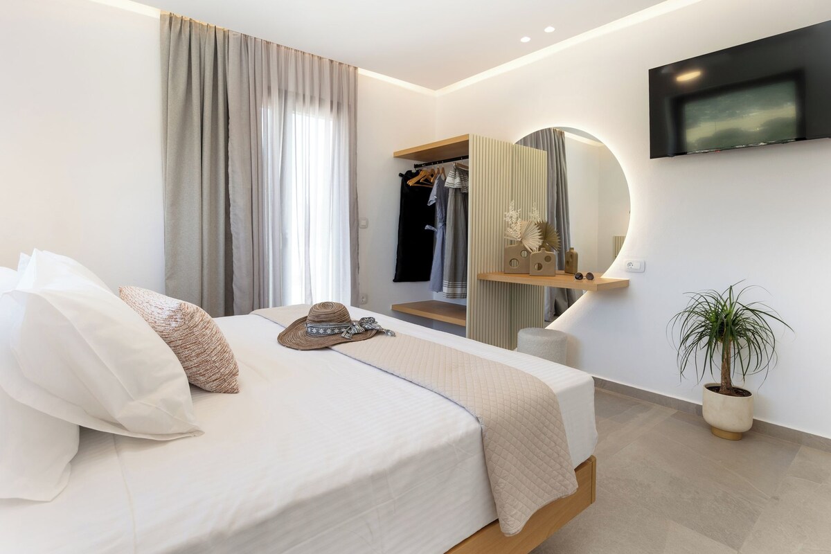 Ein modernes Hotelzimmer mit Bett, Spiegel, Fernseher und Zimmerpflanze.