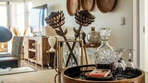 Un comedor con una mesa de madera, una jarra de cristal y copas de vino.