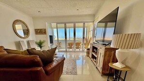 Una sala de estar con un sofá de cuero marrón, una alfombra blanca y un mueble de madera.