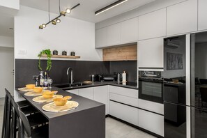 A modern kitchen with a central island, built-in appliances, and a minimalist design. - Design Apartment City Center with Balcony (Jerusalem)