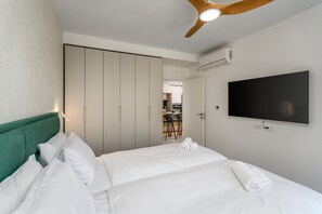 A hotel room with a bed, a TV mounted on the wall, a ceiling fan, and a wardrobe. - Design Apartment City Center with Balcony (Jerusalem)