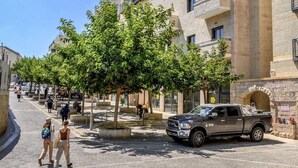 Ein mehrstöckiges Gebäude mit Balkonen, eine gepflasterte Straße und Fußgänger.
