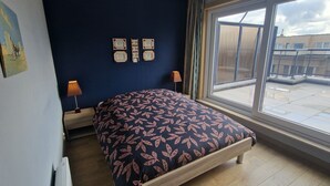 Ein Schlafzimmer mit einem Bett, einem Fenster und Blick ins Freie.