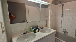 Ein Badezimmer mit zwei Waschbecken, einem Spiegel, einer Dusche und einem Handtuchhalter.