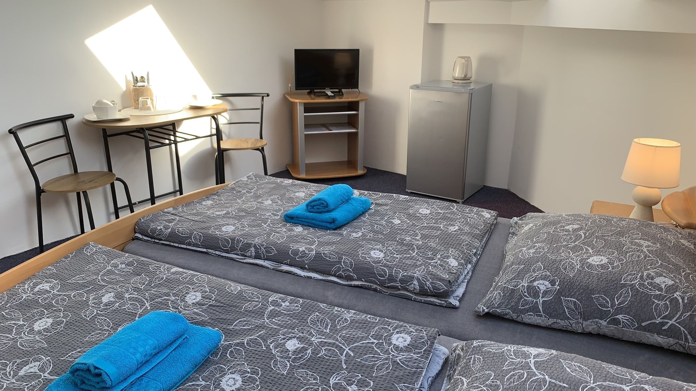 Et hotelværelse med to senge, et fjernsyn, et skrivebord og en stol.