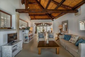 A spacious living room with a high ceiling, a television, a coffee table, and a sofa. - ELITE COLLECTION- Cala di Volpe Luxury Villa | Infinity Pool & Sea View (Cala di Volpe)