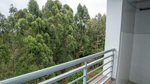 Un balcon doté d’une rambarde en métal, donnant sur une forêt dense.