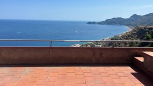 Terraço com vista para o mar e uma vila costeira.